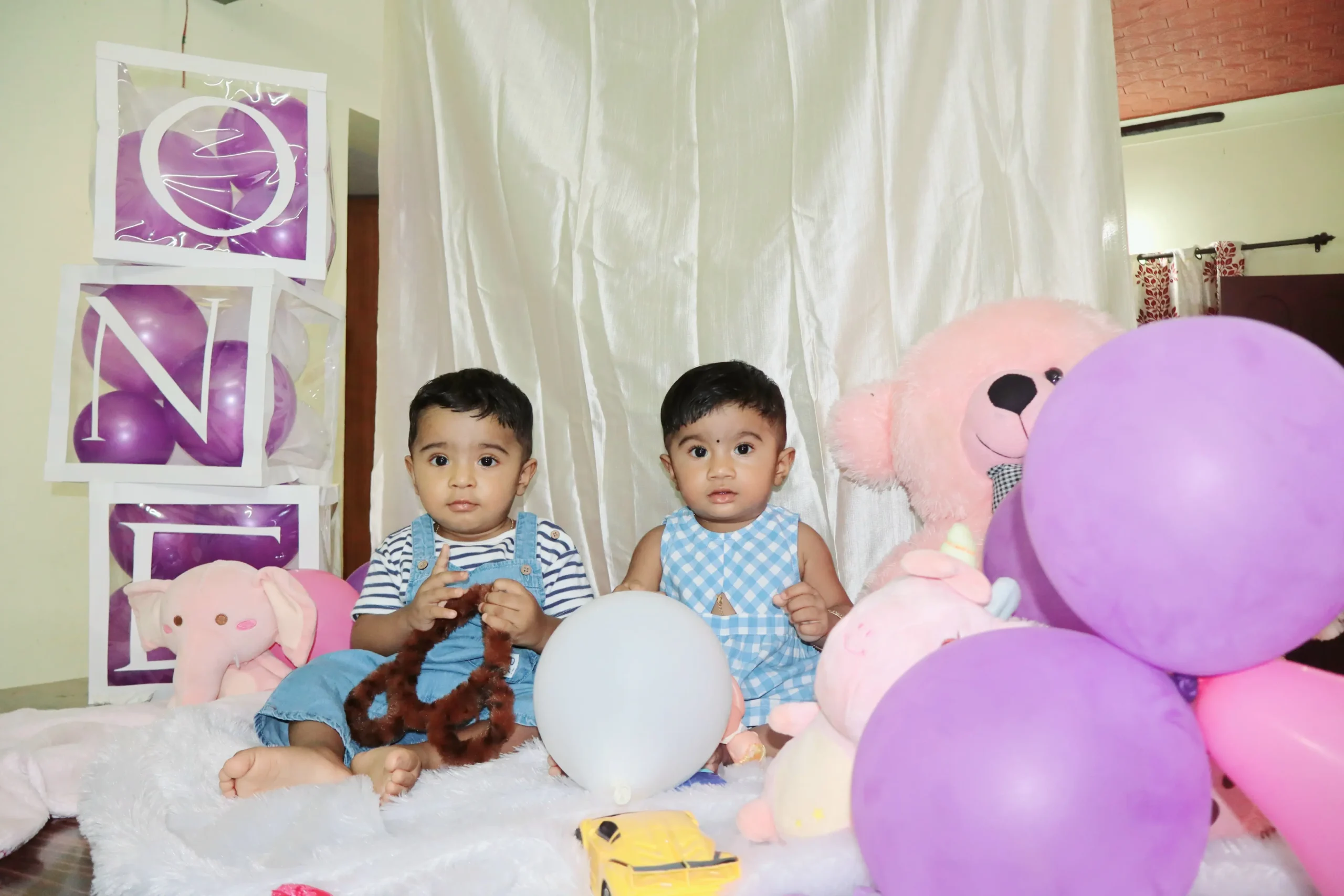 Adorable twin boy and girl celebrating their first birthday with a joyful cake smash.Kochi-based photography service for events and products.Brand shoot by freelance photographer in Kochi