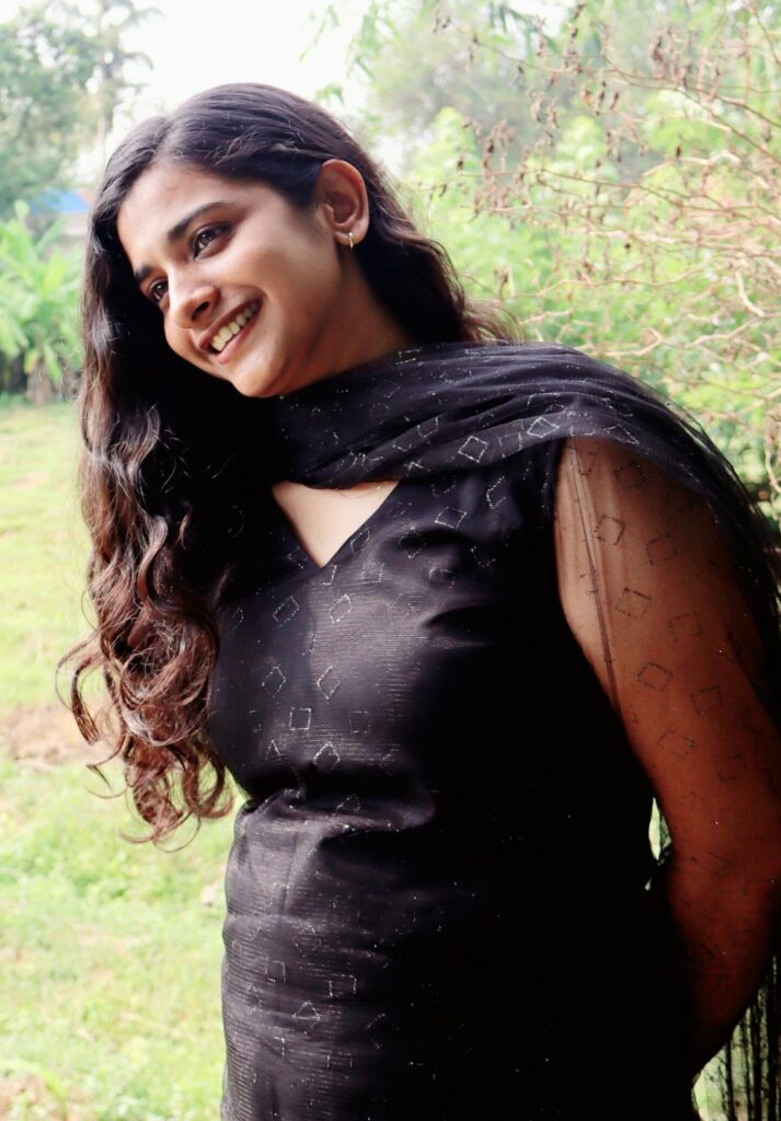 Side-angle portrait of a smiling girl in a black churidar. Freelance photographer in Kochi capturing outdoor portraits